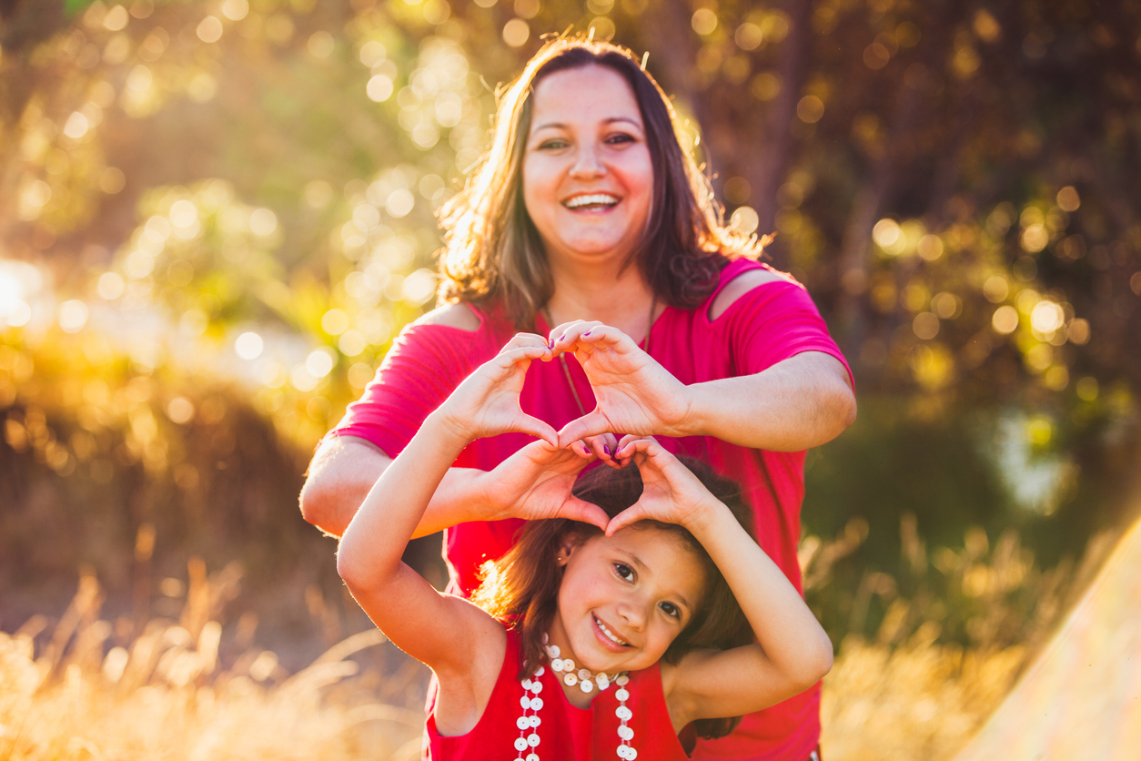 Mother and daughter making heart shape.