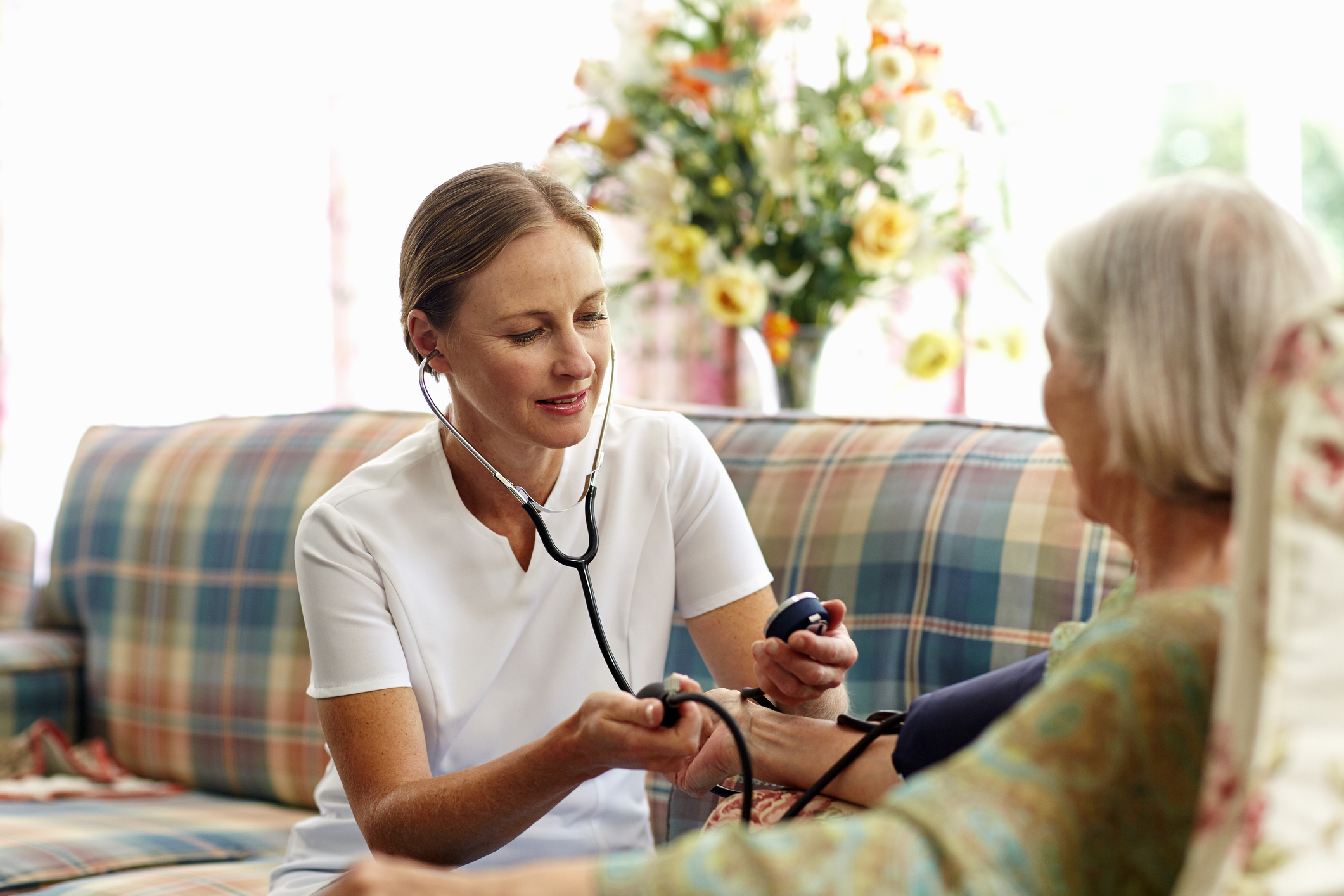 Caretaker measuring senior woman's blood pressure