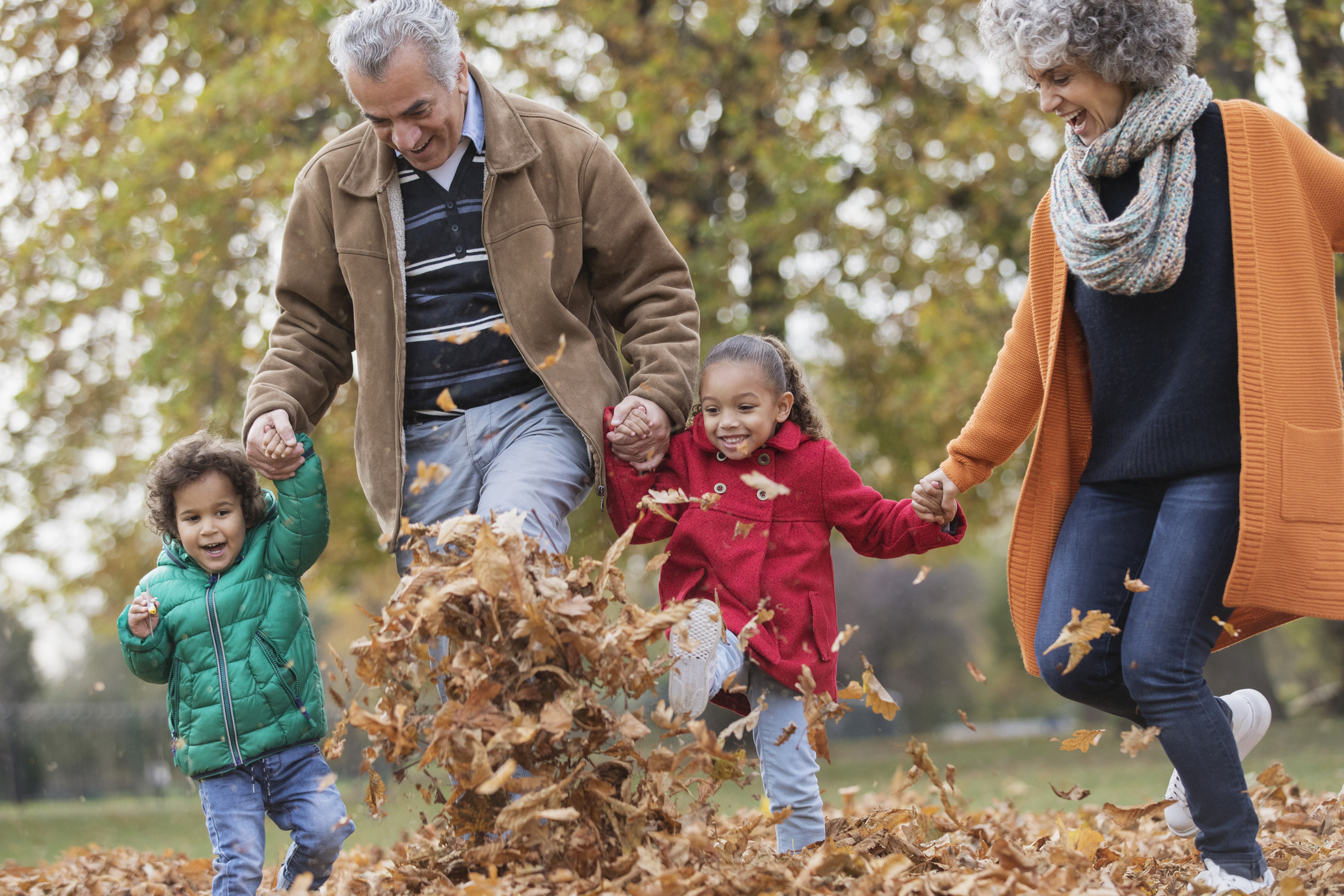 Grandparents and grandchildren kicking leaves