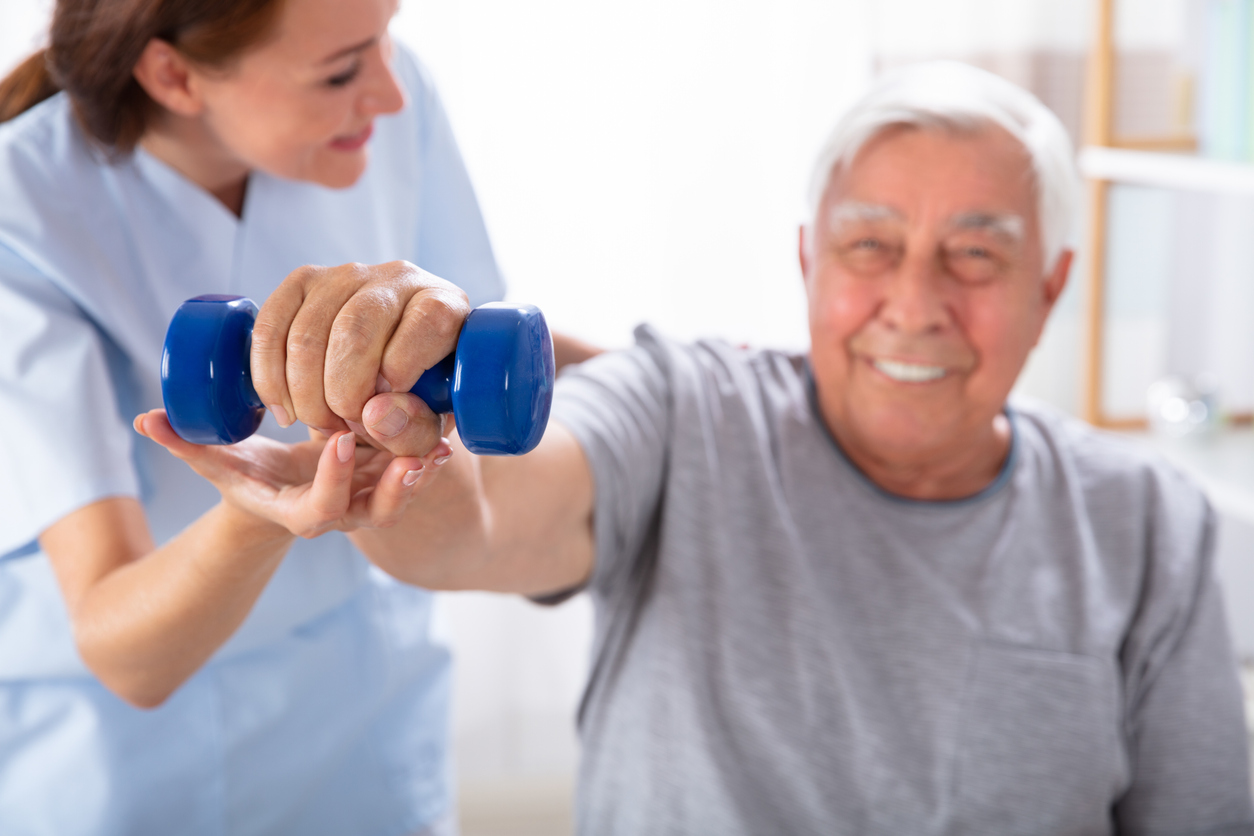 Nurse Helping Senior Man With Dumbbell Exercise